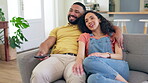 Happy couple, relax and watching tv on sofa for entertainment or online streaming together at home. Man and woman relaxing to watch movie, series or shows on living room couch indoors in comfort