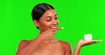 Beauty, cream and a woman pointing on a green screen background in studio for natural skincare. Portrait, product and hand gesture with a happy young female model advertising on chromakey mockup