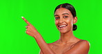 Skincare, smile and a woman pointing on a green screen background in studio for natural beauty. Portrait, space and antiaging treatment with a happy young female model advertising on chromakey mockup