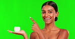 Skincare, lotion and a woman pointing on a green screen background in studio for natural beauty. Portrait, product or antiaging treatment with a happy young female model marketing on chromakey mockup
