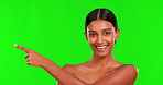 Face, beauty and a woman pointing on a green screen background in studio for antiaging skincare. Portrait, skin and natural treatment with a happy young female model advertising on chromakey mockup