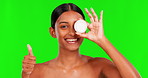 Beauty, lotion and thumbs up with a woman on a green screen background in studio for natural skincare. Portrait, yes and motivation with a happy young female model advertising on chromakey mockup