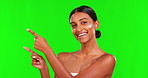 Beauty, lotion and a woman pointing on a green screen background in studio for natural skincare. Portrait, cream or antiaging treatment with a happy young female model advertising on chromakey mockup