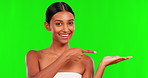 Skincare, product and a woman pointing on a green screen background in studio for natural treatment. Portrait, beauty and antiaging with a happy young female model advertising on chromakey mockup
