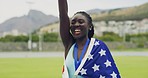 Proud and patriotic athlete becoming a champion. Gold medalist cheering and biting her medal after winning a race. Black woman celebrating a victory while wearing the USA flag on her back