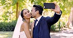 Happy wedding, bride and groom with selfie in park, special memory and celebration of marriage. Bridal couple, smile and kissing for photograph in garden to celebrate life partner, commitment or love