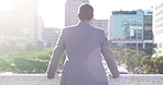 Cityscape, sunrise and business man from back with freedom, vision and view of buildings. Businessman with dream for future, success and city skyline in morning light, urban opportunity for success.