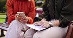 Business, closeup and women on a bench, smartphone or planning for collaboration, documents or discussion. Female professionals, freelancers or partners in a park, cellphone or mobile app for project