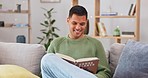 Relax, couch and man reading a book, smile and chilling at home, living room and joyful. Male person on a sofa, model and guy with literature, knowledge and education with happiness and learning 