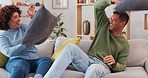 Pillow, fight and happy couple in living room for love, funny game and silly energy at home. Pillows, fighting and excited man being playful with young woman, partner and laughing together on sofa