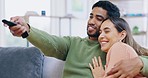 Happy couple, hug and relax watching tv for entertainment or fun streaming on living room sofa at home. Man and woman relaxing or hugging for movie, show or series and remote in cozy comfort on couch