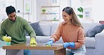 Helping, cleaning and a couple wiping table of dust, spraying disinfectant and happy with home chores. Smile, together and a man and woman doing housework, washing a desk and support in housekeeping