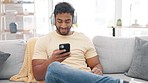 Headphones, phone and man listening to music on a sofa at home feeling relax and happy. House, web radio and audio streaming of a male person in a lounge and living room on a mobile on a couch