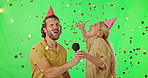 Green screen, party and couple on karaoke for a birthday celebration with confetti isolated in a studio background. Microphone, song and party hats to celebrate together and feel happy music