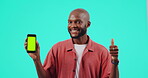 Green screen, phone and man thumbs up for success, yes and vote, like or emoji with face of winner. Mobile mockup, tracking marker and african person winning or ok hands isolated on studio background