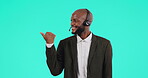 Portrait, call center and pointing with a black man consultant on a blue background in studio for customer service. Contact us, crm and support with a happy telemarketing employee showing information