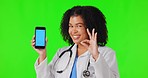 Ok sign, woman and doctor with phone on green screen in studio isolated on background. Smartphone, okay hand and African medical professional with happy portrait, marketing space and tracking markers