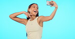 Woman, selfie and happiness with influencer and social media post, memory and carefree on blue background. Mockup space, energy with young female person smile and pose in picture with live stream