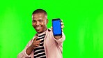 Happy black man, phone and mockup on green screen for advertising against a studio background. Portrait of African male person pointing with mobile smartphone app or tracking markers on mock up space