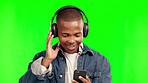 Phone, music headphones and black man on green screen in studio isolated on a background. Radio, listening and happy African person dancing to audio playlist, jazz podcast or streaming hip hop sound.