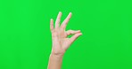 Closeup, perfect and hand with okay, green screen and support against a studio background. Zoom, ok gesture and vote with agreement, approve and showing signal with review, feedback and emoji symbol