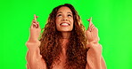 Happy, fingers crossed and a woman with a wish or hope on green screen thinking of dream. Latino model person with hand sign or emoji while praying for good luck for lottery on a studio background