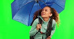 Young woman, umbrella and rain by green screen for travel, adventure and check sky with cover in mockup. Student girl, parasol and protection from winter weather with walking, journey and hiking