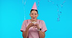 Birthday, party and balloons with a nurse woman in studio isolated on a blue background for celebration. Smile, healthcare and a happy female medicine professional blowing out a candle on a cupcake