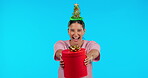 Excited face, Christmas and a woman with a gift for happiness isolated on blue background in a studio. Happy, party and portrait of a girl giving gift for celebration or birthday with a festive box