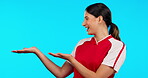 Presentation, information and a woman soccer player getting ready in studio isolated on a blue background. Football, fitness and sports with a happy young female athlete marketing or advertising