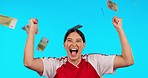 Woman, money rain and happy for sport with fist celebration, financial success or gambling profit by blue background. Young girl, winner or athlete with cash in air, bonus prize and excited face