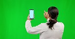 Woman, phone and mockup on green screen for advertising, research or browsing against a studio background. Back of female person on mobile smartphone app with mock up display and tracking markers