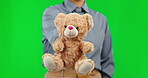 Teddy bear, green screen and person with charity gift for care, support and trust isolated in a studio background. Toy, soft and therapist giving a present or stuffed animal for comfort for a friend