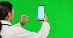 Woman, doctor and phone with mockup on green screen for advertising or research against a studio background. Back of female person on mobile smartphone app with mock up display and tracking markers