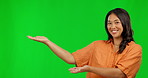 Happy asian woman, hands and advertising on green screen for presentation against a studio background. Portrait of female person showing palm for advertisement, news or marketing on mockup space