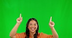 Excited asian woman, pointing and advertising on green screen against studio background. Female person finger point for advertisement, sale discount or deal and notification, alert or news on mockup