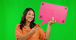 Asian woman, speech bubble and pointing on green screen for comment against a studio background. Portrait of happy female person with smile and icon for feedback, social media and tracking markers