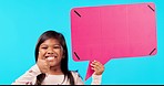 Happy little girl, thumbs up and pointing to speech bubble on mockup for chat against a blue studio background. Portrait of female child or kid smile with like emoji, yes sign or social media success