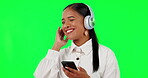 Happy woman, headphones and listening to music on green screen with phone against a studio background. Calm female person with headset and mobile smartphone app for audio streaming or sound track