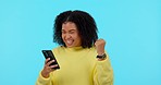 African woman, phone and celebration in studio for winning, goals or success in gambling, fintech or blue background. Girl, student and winner with smartphone for online contest, profit or investment