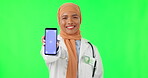 Muslim woman, doctor and phone mockup on green screen for advertising against a studio background. Portrait of female medical or healthcare professional with mobile smartphone app or tracking markers