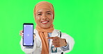 Muslim woman, doctor and pointing to phone mockup on green screen in advertising against a studio background. Portrait of female medical or healthcare expert point to smartphone with tracking markers