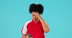 Stress, phone and female athlete in a studio checking football or sports score or results online. Technology, frustration and upset woman soccer player with a cellphone isolated by a blue background.