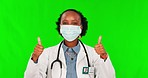 Thumbs up, mask and a doctor black woman on green screen background in studio for healthcare treatment. Covid, smile or walking with a female medicine professional on chromakey mockup for motivation