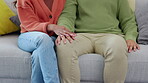 Support, couple holding hands and together on a sofa for empathy in living room. Love or sympathy, comfort or apology and people sitting on couch with hand touching for gratitude at their home