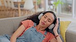 Depression, phone and woman on a sofa with music, unhappy and tired in her home. Break up, text and female person heart broken a living room while streaming podcast for mental health, grief or stress