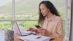 Laptop, phone and a business woman in the office at her desk doing research on a report for work. Computer, communication and notebook with a young corporate employee working in a glass workplace