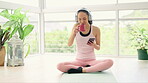 Coffee, phone and woman with headphones on yoga mat for streaming video in home. Mobile, drink tea and pilates person happy on relax break after exercise, training or fitness while listening to music