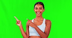 Happy woman, fitness and pointing on green screen for advertising against a studio background. Portrait of fit, active and sporty female person with smile in advertisement or show on mockup space