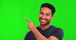 Pointing, happy and face of Asian man on green screen for promotion, approval and agreement. Advertising, branding and portrait of male person with smile, news and announcement hand gesture in studio